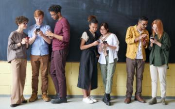 Group of students lined up in a classroom all looking at their phones