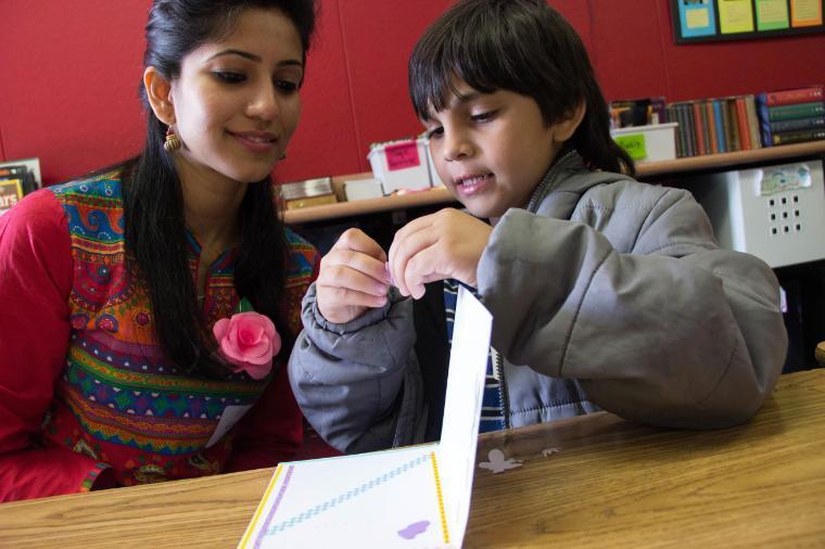 Santa Clara student reads a book alongside a grade school student 