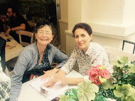 Two people sitting at a table with conference materials and flowers.