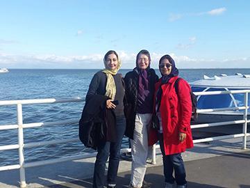 Three people standing together on a deck with ocean background.