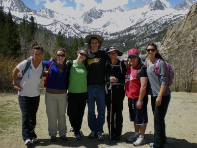 Group of students standing outdoors with snow-capped mountains in the background.