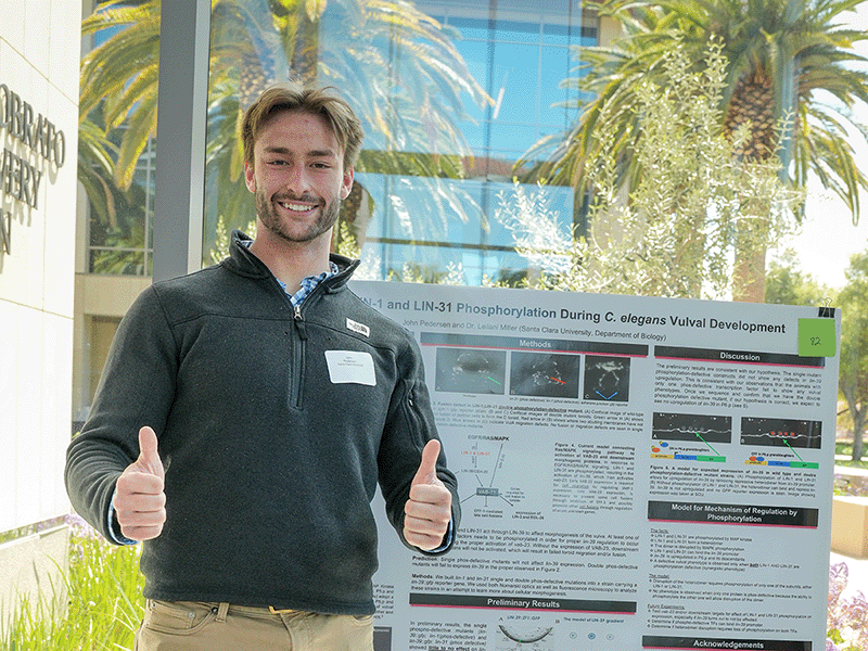 A student stands by his poster