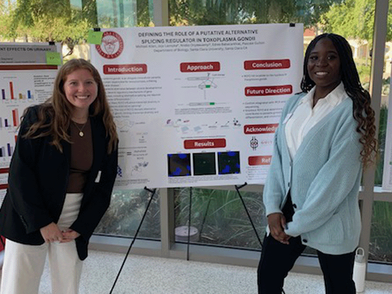 Two students stand by their poster