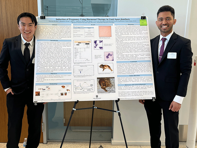 Two students stand next to their poster