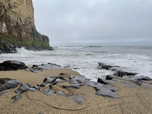 Low shot of a beach with waves beating against rocks and a cliff face