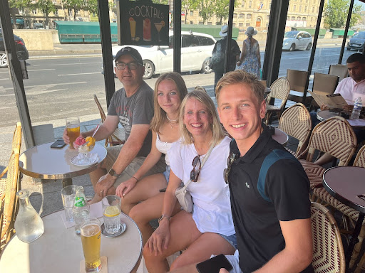 Four people seated at an outdoor café, smiling at the camera.