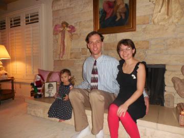 Two people sitting by a fireplace with Christmas decorations.