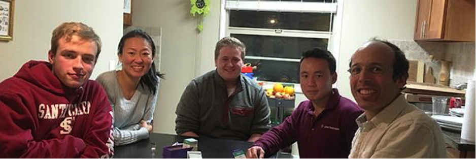 A group of five people sitting and smiling in a kitchen.