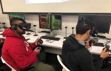 Students in a classroom using computers and virtual reality headsets.