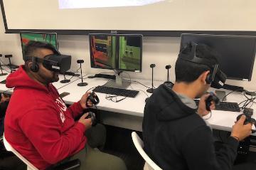 Students wearing VR headsets at computers in a classroom.