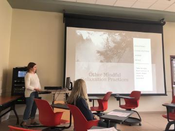 Person presenting to a small group in a classroom.