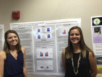 Two people stand by a presentation titled 