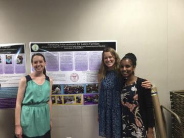 Three people in front of a poster on Latino families.