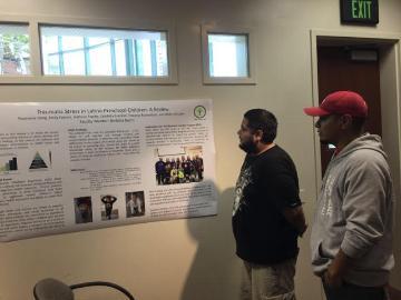 Two people looking at posters on a wall in a preschool.