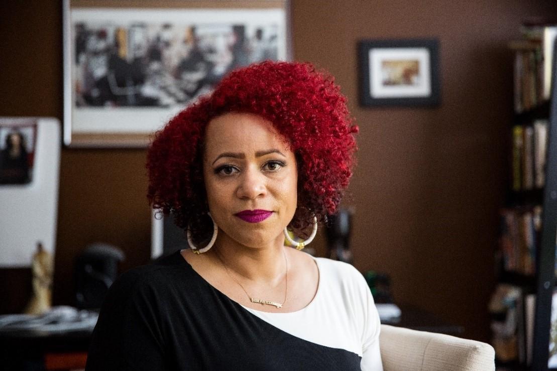 Alt text: Nikole Hannah-Jones sitting in an office with framed photos on the wall.