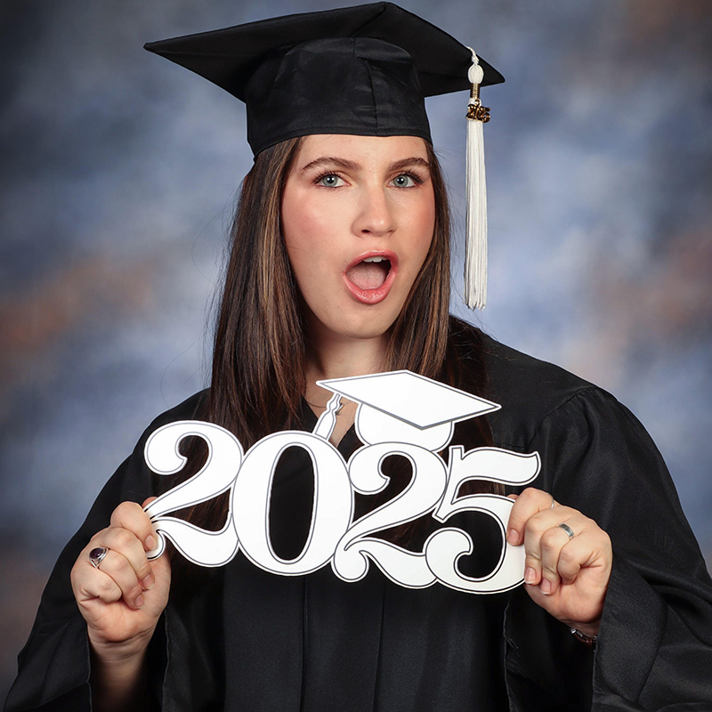 Caitlin Gronowki in black graduatios cap and gown holding a 2025 cutout