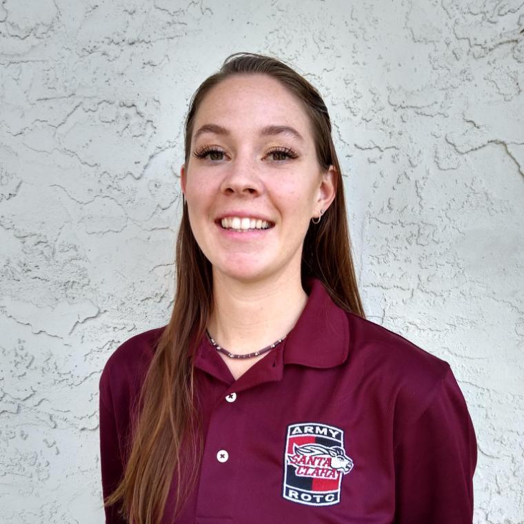 A person smiling wearing a maroon ROTC polo shirt.