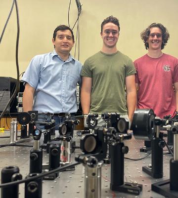 3 Physics lab students in front of equipment