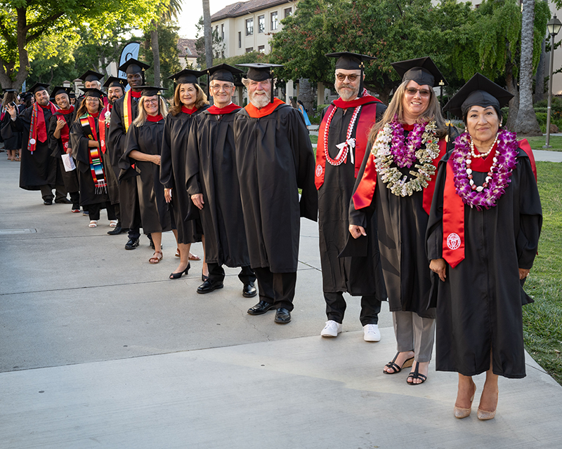 graduates in their regalia line up to process to commencement