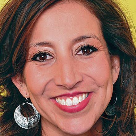 A woman smiling against a yellow background.