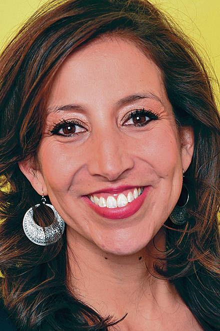 A woman smiling against a yellow background.