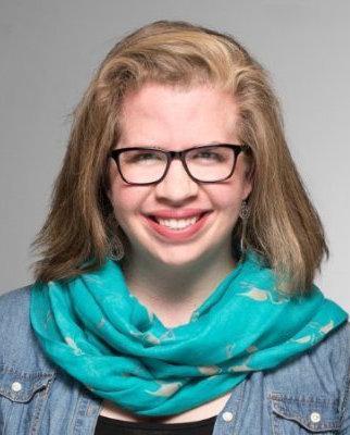 A person wearing glasses and a teal scarf, smiling.