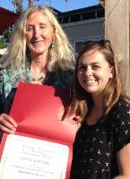 Two people smiling; one holds a red folder with a white paper inside.