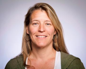 A woman smiling with a plain background.