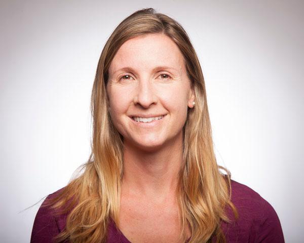 A person smiling at the camera against a plain background.