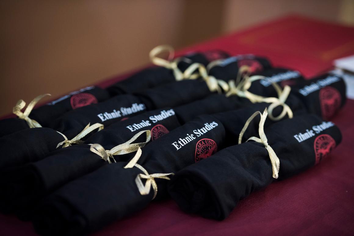 Rolled diplomas tied with ribbons on a red table at a reception.