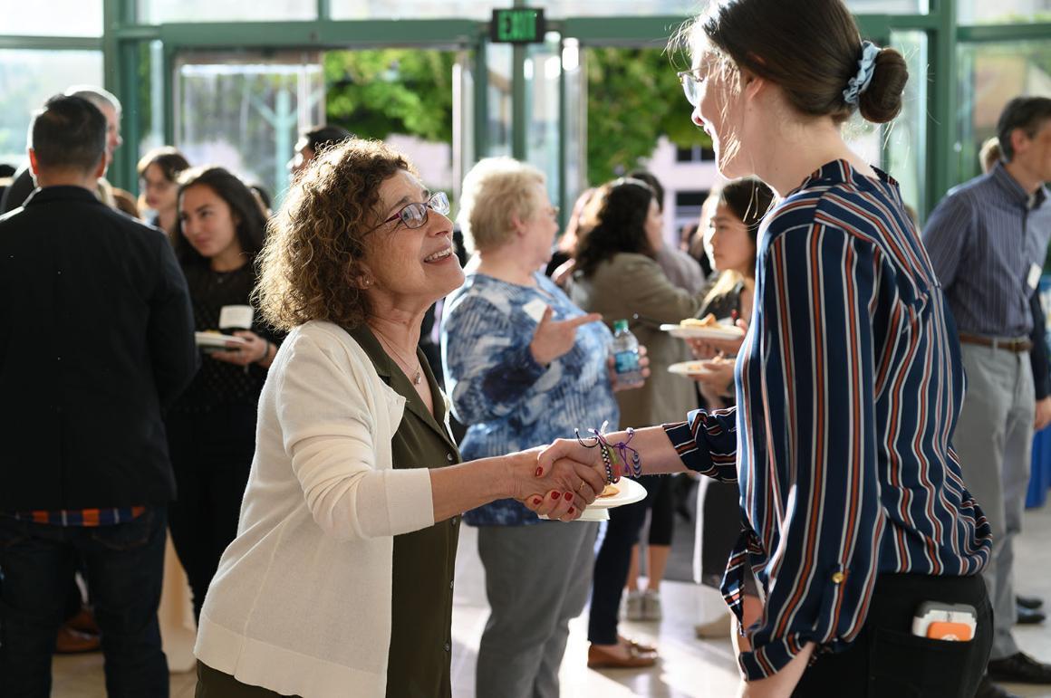 A community partner shaking hands with a current student 