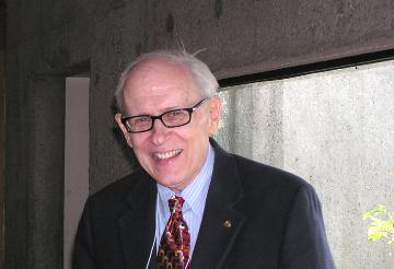 An older gentleman in a suit and tie, wearing glasses.