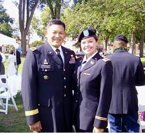 Two people in military uniforms smiling at an outdoor event.