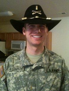 A person in military uniform and a wide-brimmed hat smiling.