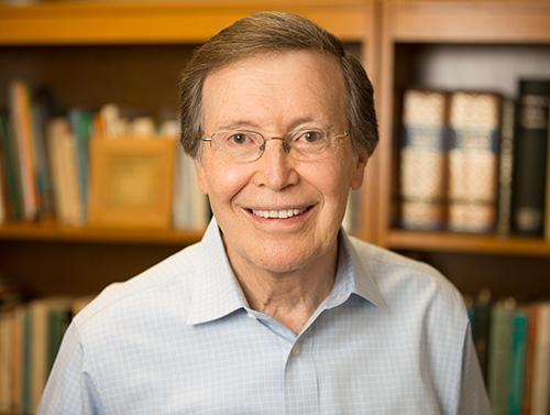 A person smiling in front of bookshelves.