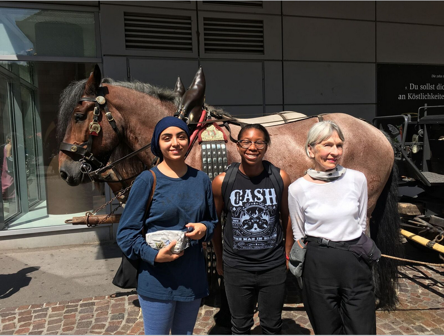 Three people standing in front of a horse and cart in Freiburg.