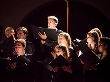 A conductor leading a choir in a performance.