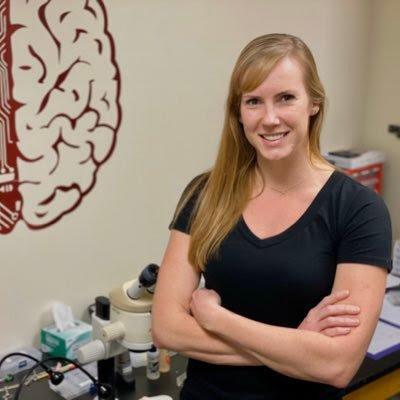 A person standing in an office with a brain diagram on the wall.