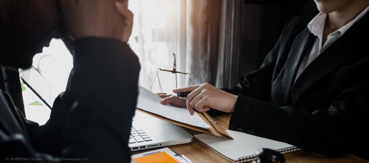 man with head in hands and woman across from him at desk