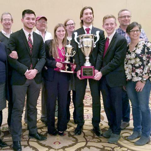 A group of people posing with a trophy at the Ethics Bowl.