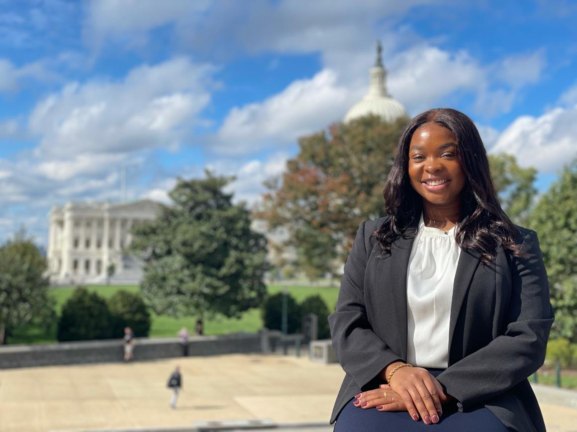 A person sitting outside with a historic building in the background.