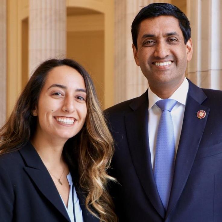 Two individuals standing inside a building, smiling for a photograph.