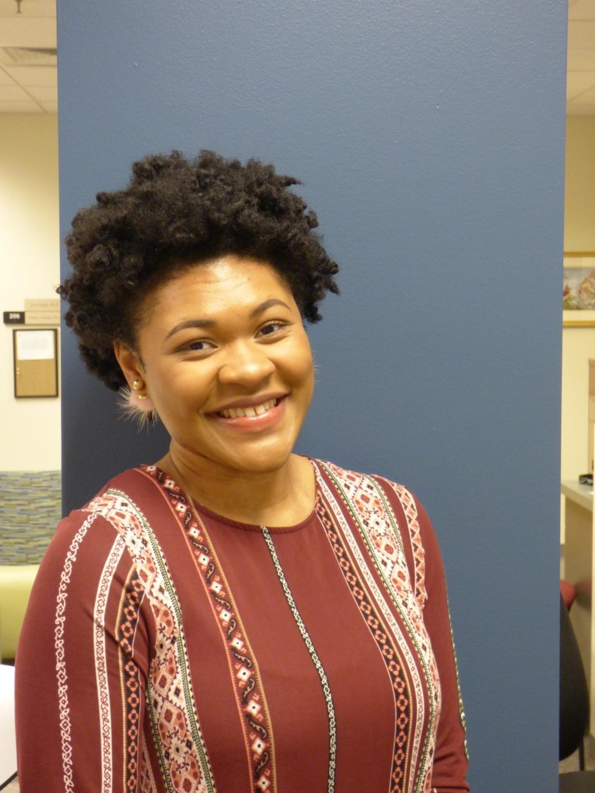 A person smiling in a red and white patterned shirt.