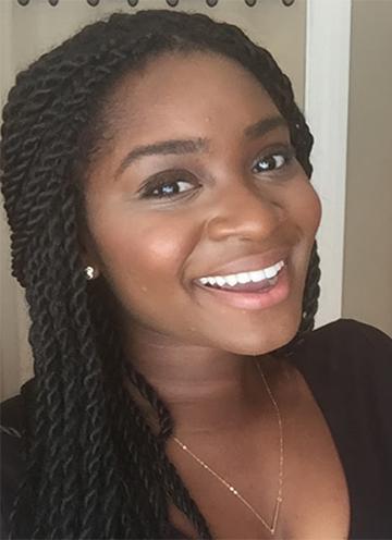 Smiling woman with braids wearing a black top.