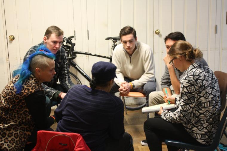 A group of people sitting and talking, with a video camera nearby.