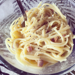 Spaghetti carbonara with bacon and black pepper in a bowl.