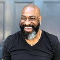 A man smiling in front of a blue background.