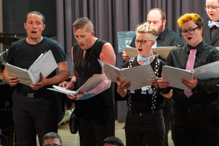 People singing from sheet music in the New Voices Choir.