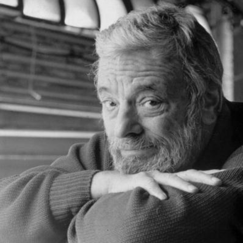 Black-and-white photo of Stephen Sondheim smiling, leaning on his arms.