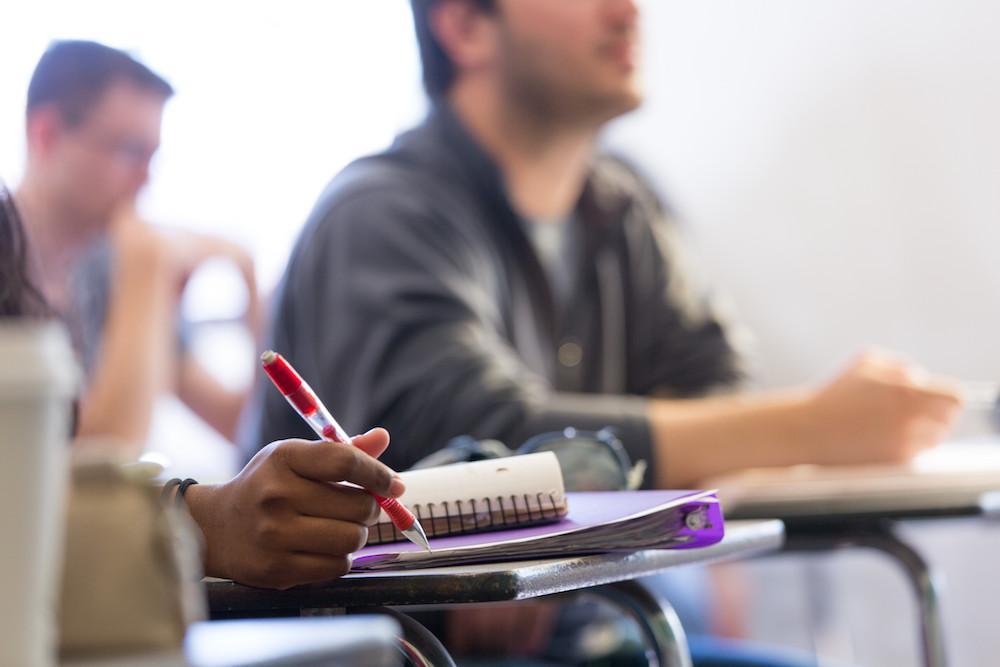 Students attentively taking notes at their desks during class.